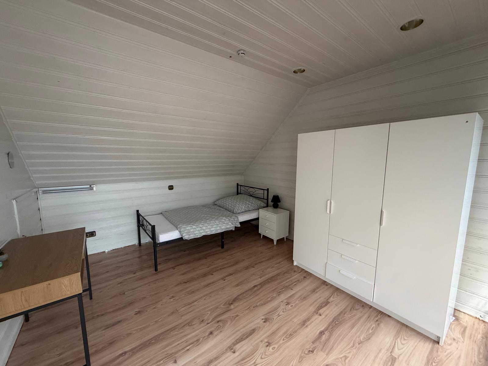 Zimmer 9: Blick auf das Einzelbett und den weißen Kleiderschrank.