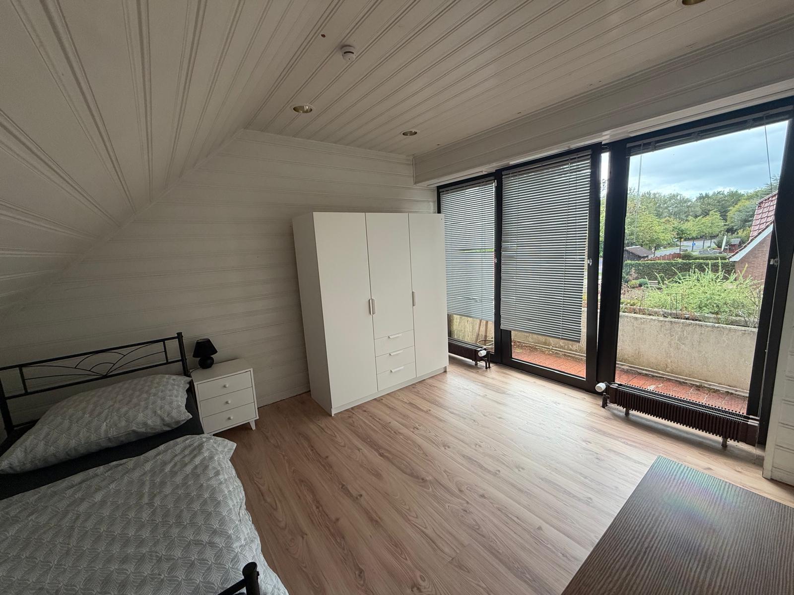 Zimmer 9 am Seitenkanal 20 in Meppen: aktuelle Einrichtung mit Einzelbett, weißem Kleiderschrank und Balkonzugang